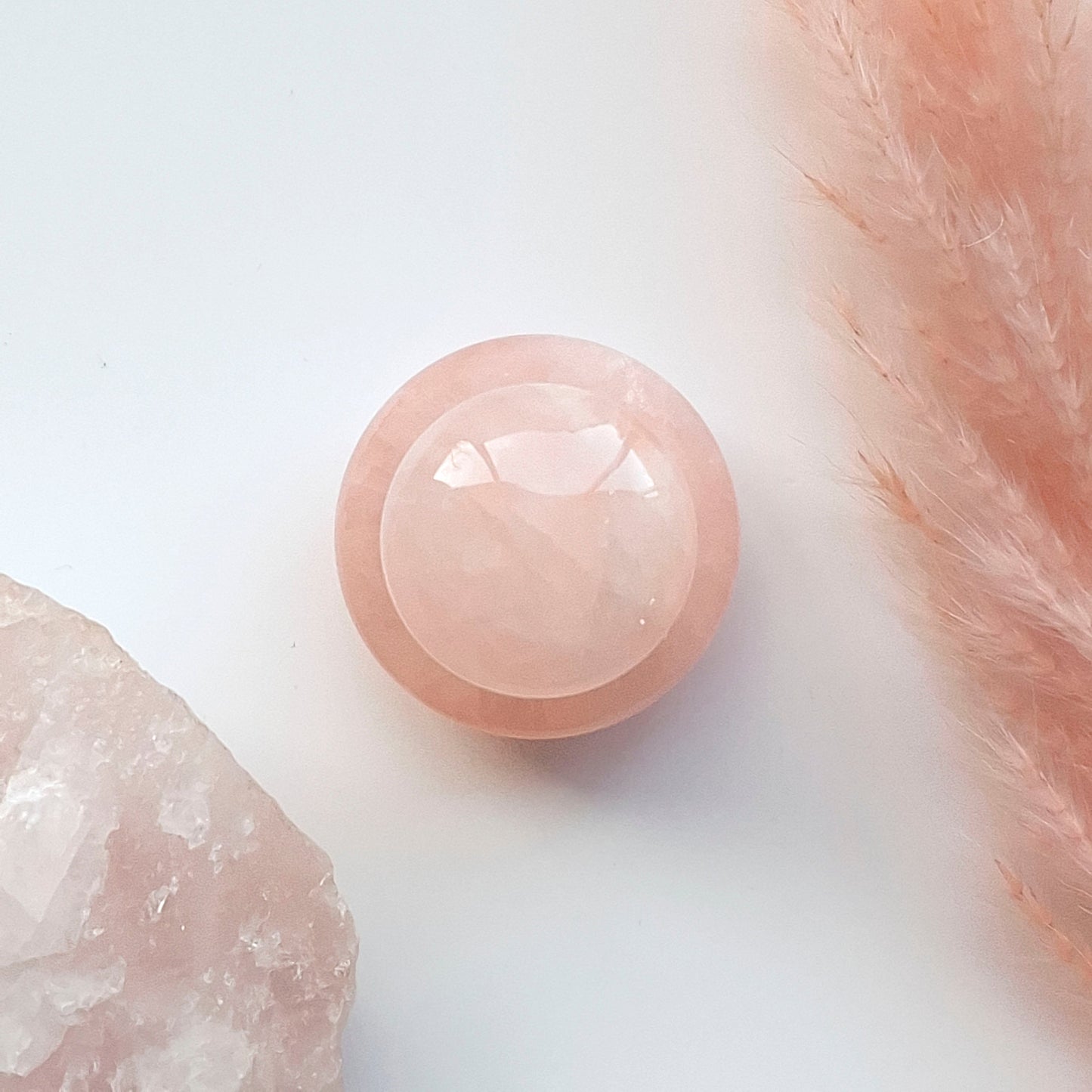 Gua sha rozenkwarts paddenstoel bovenaanzicht met ruwe rozenkwarts steen en roze pluim